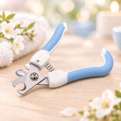 Coupe-griffes pour chat ouvert, à poignées bleues et blanches et lames métalliques, posé sur une surface en bois clair