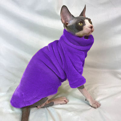 Pull pour chat coloris violet à col roulé, porté par un chat sans poils gris et blanc assis de profil sur un drap blanc