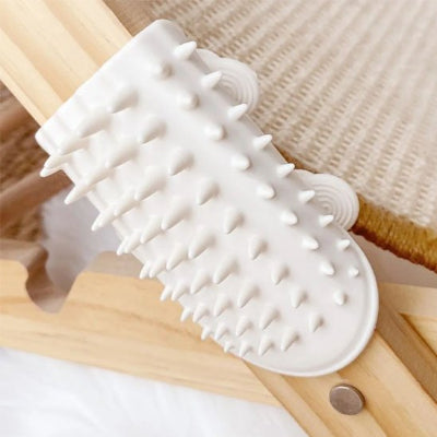 Brosse à chat blanche en silicone aux picots souples posée sur un plan en bois clair