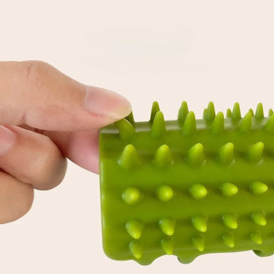Main tenant une brosse à chat verte pour montrer la souplesse de ses picots en silicone