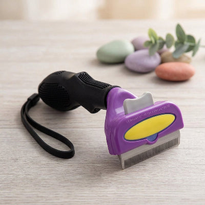 Brosse violette pour chat à poil long, avec manche noir, dragonne et dents métalliques, posée sur une surface en bois clair