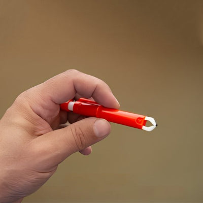 Pince à tiques rouge tenue entre les doigts, avec son embout blanc ouvert visible